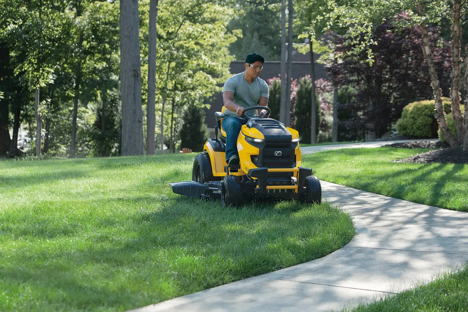 Cub Cadet XT2 SLX50 lawn tractor mowing along a curved sidewalk