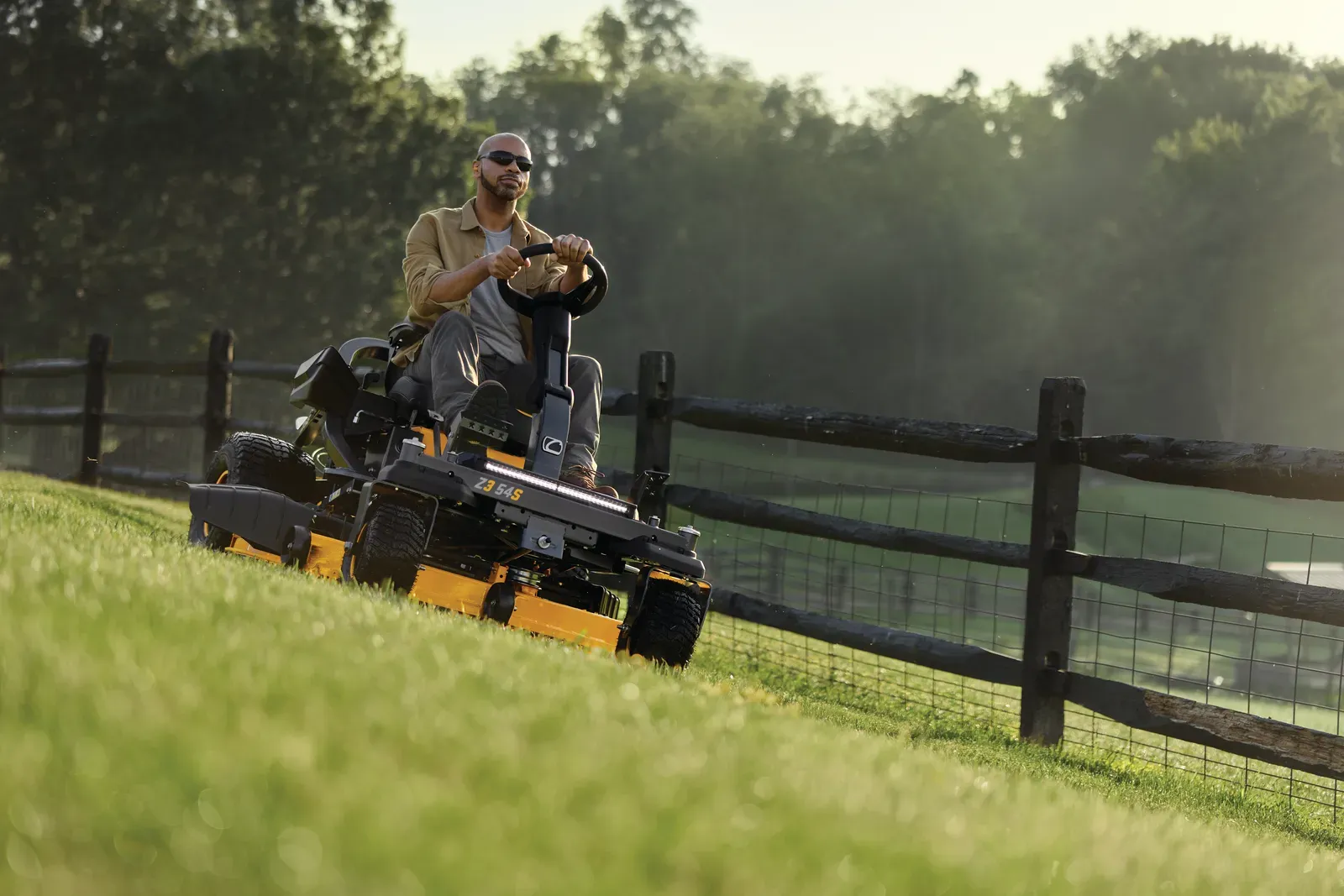 Cub Cadet Ultima Z3 54S steering-wheel zero-turn mowing along a fence line on a grade