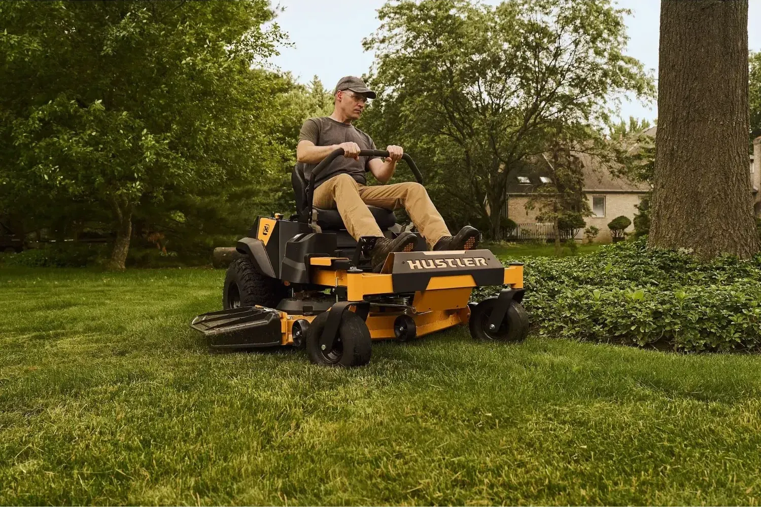 Lap-bar zero-turn mower trimming close around a tree trunk